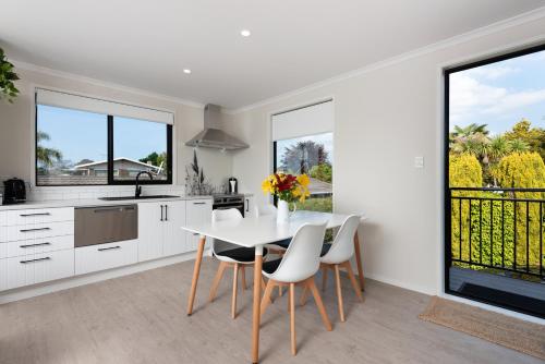 a kitchen with white cabinets and a table and chairs at Luxury Apartment retreat in Tauranga