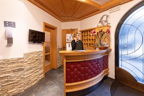 a woman sitting at a bar in a barbershop at Hotel Thuinerwaldele in Vipiteno