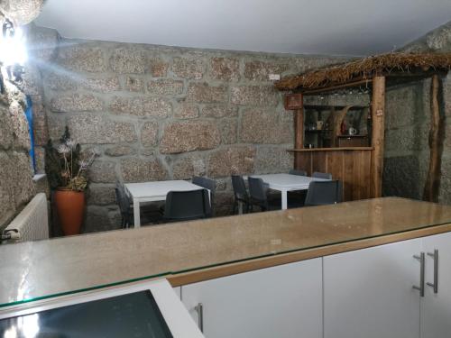 ein Zimmer mit Tischen und Stühlen und einer Steinmauer in der Unterkunft Quinta de São Simão Turismo e Eventos in Vieira do Minho