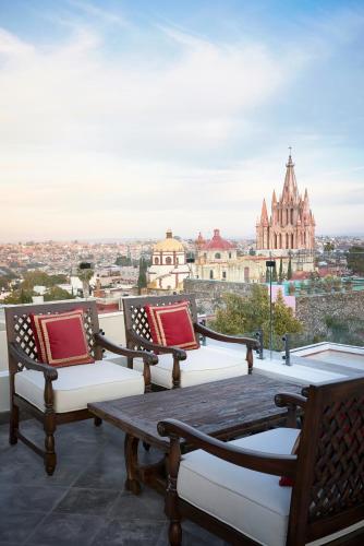 a balcony with three benches and a table with a view at Casa de Sierra Nevada, A Belmond Hotel, San Miguel de Allende in San Miguel de Allende