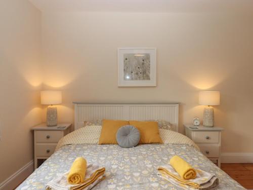 a bedroom with a bed with yellow pillows and towels at Mimosa in Dawlish