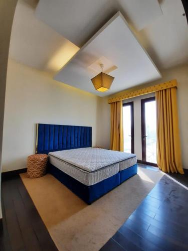 a bedroom with a large bed with a blue headboard at 1Bedroom Furnished Apartment in Dubai