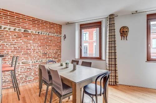 a dining room with a table and a brick wall at Duplex Tolosa - Pont-Neuf, Dôme de la Grave, 2 BDRs 85m2, AC, Free private car park 200m away - T3 85m2 avec clim, parking couvert gratuit à 200m in Toulouse