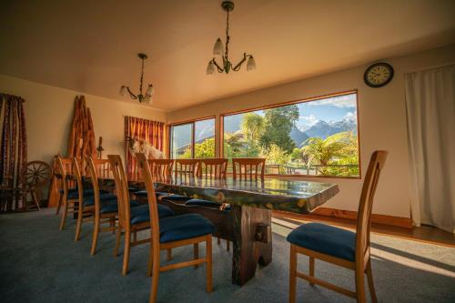 ein Esszimmer mit einem Tisch und Stühlen sowie einem großen Fenster in der Unterkunft Ropatinis Bed & Breakfast in Fox Glacier