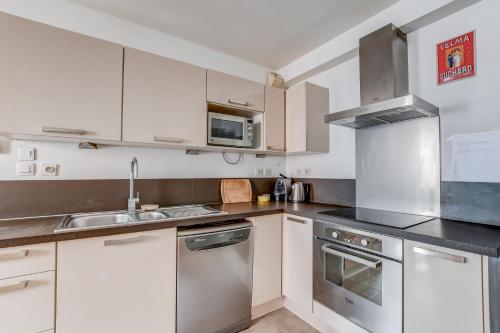une cuisine avec des armoires blanches et des appareils en acier inoxydable dans l'établissement Duplex Tolosa - Pont-Neuf, Dôme de la Grave, 2 BDRs 85m2, AC, Free private car park - T3 85m2 avec clim, parking privé gratuit, à Toulouse