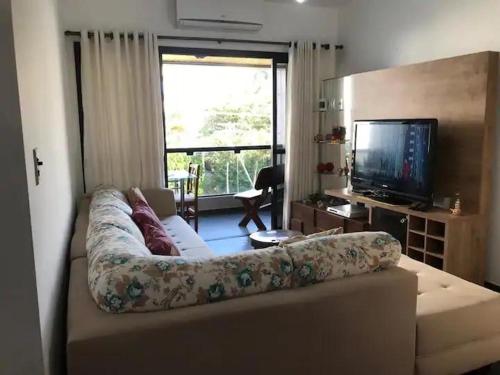 ein Wohnzimmer mit einem Sofa und einem TV in der Unterkunft Apartamento no guaruja- praia enseada in Guarujá