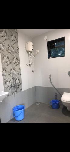 a bathroom with a toilet and two blue buckets at Vickys Guest House in Malvan