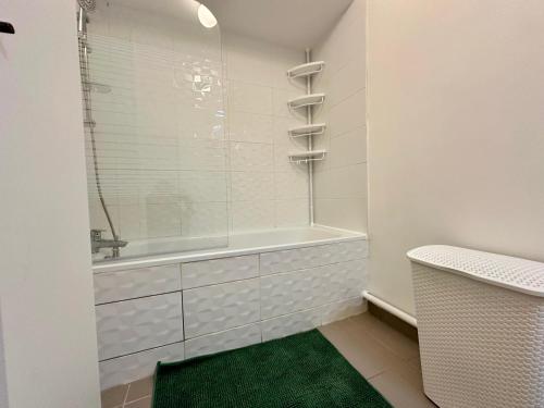 a bathroom with a shower and a tub and a green rug at Agréable 3 pièces avec Parking à La Courneuve Gare by immo Kit bnb in La Courneuve