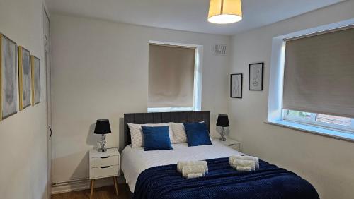 a bedroom with a large bed with blue pillows at Chic Two Bedroom Apartment in the Heart of Battersea Modern and Comfy in London