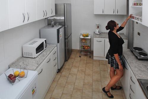 サンティアゴにあるRESIDENCIA WENUIKANの冷蔵庫の台所に立つ女性
