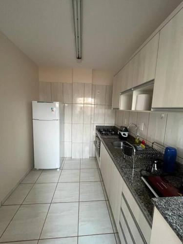 a kitchen with a white refrigerator and a sink at Apto Aconchegante Central! 23 in Toledo