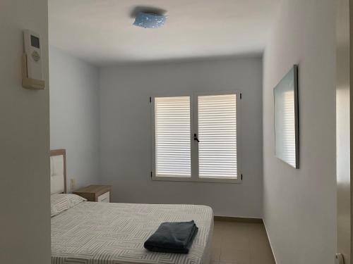 - une chambre blanche avec un lit et 2 fenêtres dans l'établissement La casita de la playa, à Oliva