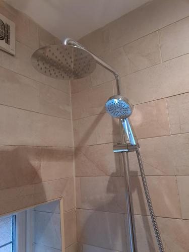 a shower with a shower head in a bathroom at Garden Room in Bromsgrove