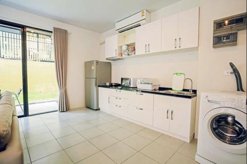 a kitchen with white cabinets and a stainless steel refrigerator at Enjoy Samui Residences Pause by Replay in Koh Samui 