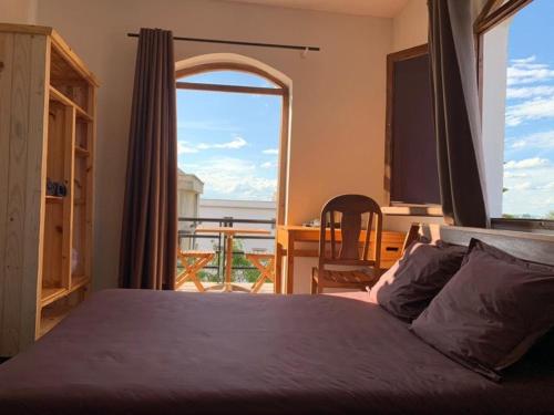 ein Schlafzimmer mit einem Bett und einem großen Fenster in der Unterkunft Iarimbato Hotel in Antananarivo
