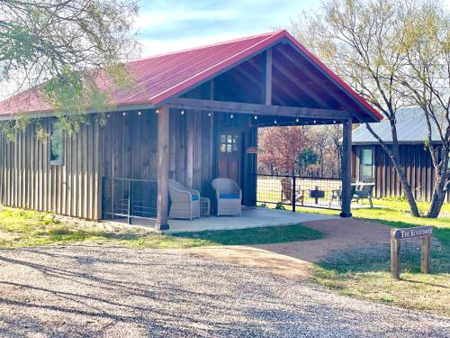 a small cabin with a red roof and a porch at The Kingfisher Cabin 15MIN to Magnolia Baylor in Elm Mott