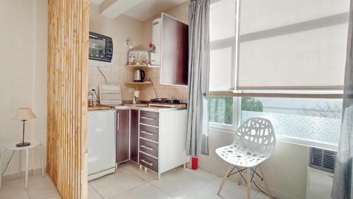 cocina pequeña con nevera blanca y silla en Petit appartement en el corazón de Bariloche en San Carlos de Bariloche