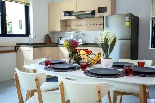 a kitchen with a white table with plates and chairs at Enjoy Samui Residences Pause by Replay in Koh Samui 