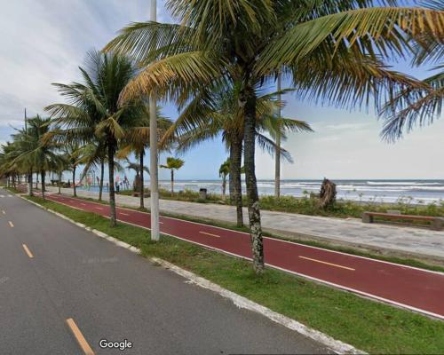 una carretera con palmeras al lado de una playa en Aconchegante casa a 50m da praia, en Praia Grande