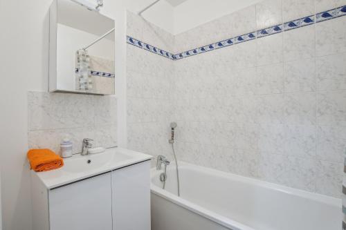 Baño blanco con bañera, lavabo y espejo en Chic and spacious apartment with balcony, en Ivry-sur-Seine