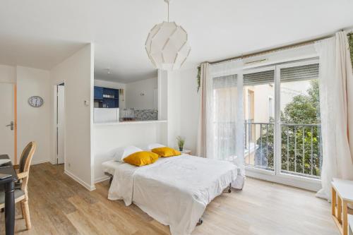 Dormitorio blanco con cama y ventana grande en Chic and spacious apartment with balcony, en Ivry-sur-Seine