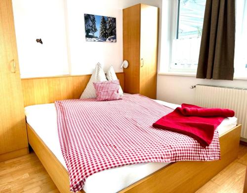 a bed with a red and white checkered blanket on it at Ferienwohnungen Kapp in Tröpolach