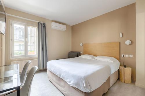 a bedroom with a large bed and a desk and a window at Marmotel Etoile in Paris