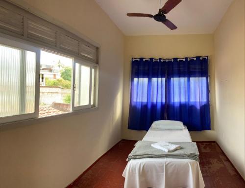 a room with a bed with a ceiling fan and a window at Pousada Família Guarapari in Guarapari