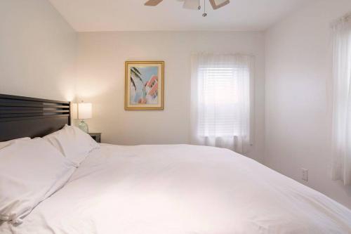 a white bed in a white bedroom with a window at Spacious Oceanview Villa (Sleeps 22) in New London