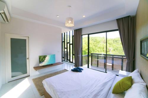 a bedroom with a large bed and a large window at Enjoy Samui Residences Pause by Replay in Koh Samui 