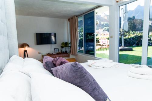 Una cama blanca con almohadas moradas en una habitación con ventana. en DUBAI by luxury Atitlan, en San Pedro La Laguna
