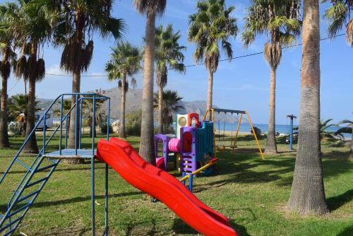 - une aire de jeux avec toboggan dans un parc planté de palmiers dans l'établissement La Palma Apartments,a beachfront paradise!, à Georgioúpoli