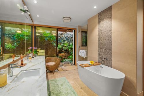 a bathroom with a tub and a large window at 2 BR Luxury Oceanview Condo in Kukuiula in Koloa