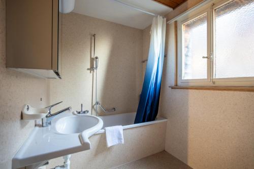 a bathroom with a sink and a blue shower curtain at Chalet Seehus Iseltwald in Iseltwald