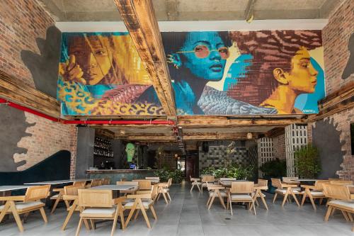 a room with tables and chairs and a mural on the wall at Hotel Zelva Negra in Medellín