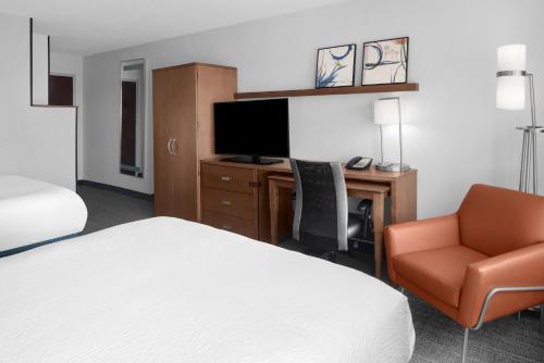 a hotel room with a bed and a desk and a chair at Courtyard by Marriott Cypress Anaheim / Orange County in Cypress