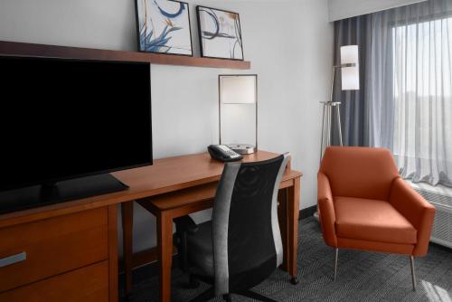 a hotel room with a desk with a television and a chair at Courtyard by Marriott Cypress Anaheim / Orange County in Cypress