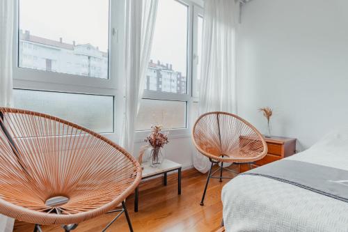 een slaapkamer met 2 stoelen, een bed en ramen bij La terrazuca in Santander