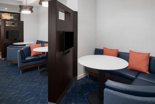 a waiting room with couches and tables and a tv at Courtyard by Marriott Cypress Anaheim / Orange County in Cypress