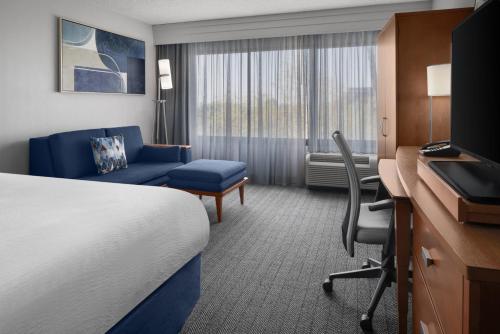 a hotel room with a bed and a chair and a desk at Courtyard by Marriott Cypress Anaheim / Orange County in Cypress