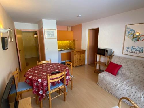 Cette petite chambre comprend une table et un canapé. dans l'établissement Appartement 37m² avec balcon, 500m centre village et pistes ski, parking privé - Autrans - FR-1-737-40, à Autrans