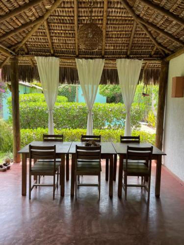 uma mesa de jantar e cadeiras num pavilhão em Casa Jasmim Imbassaí-BA em Mata de Sao Joao