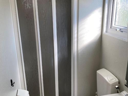 La salle de bains est pourvue de toilettes blanches et d'une fenêtre. dans l'établissement Chalet Recreatiepark Duinhoeve 1, à Udenhout