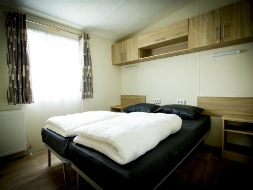 een groot bed in een kamer met een raam bij Recreatiepark Duinhoeve 9 in Udenhout