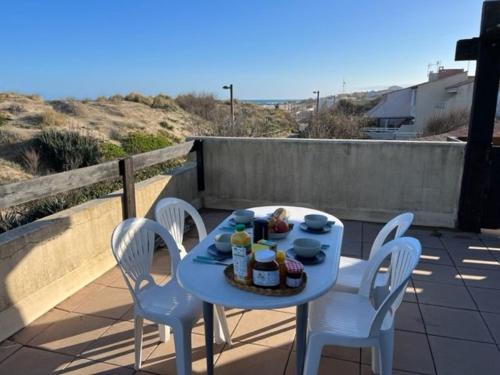 - une table bleue avec des chaises et de la nourriture sur la terrasse dans l'établissement Appartement T3 à Cap d'Agde, 6 pers, au bord de la plage avec parking et terrasse - FR-1-749-13, au Cap d'Agde