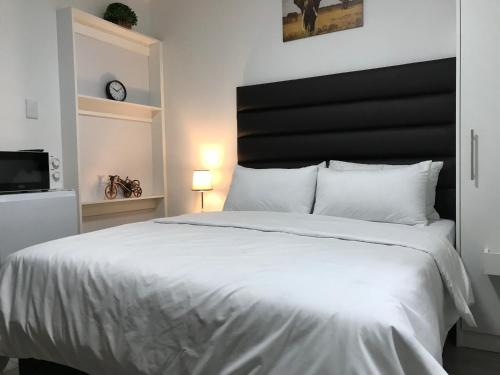 a bedroom with a large white bed with a black headboard at The Affectionate One in Louis Trichardt