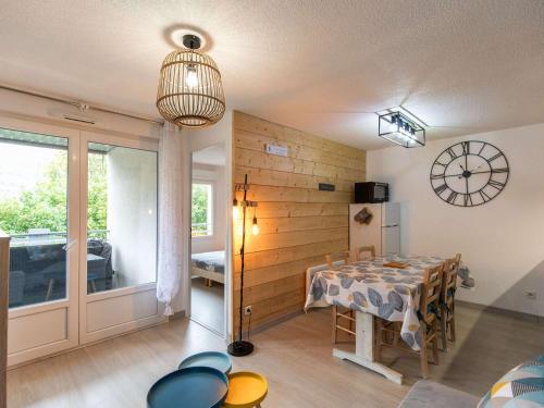 a dining room with a table and a clock on the wall at Appartement T2 cabine, terrasse, piscine, parking, proche commodités et ski, Luz-Saint-Sauveur - FR-1-402-131 in Luz-Saint-Sauveur