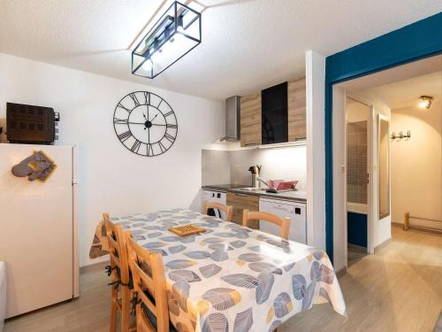 une salle à manger avec une table et une cuisine avec une horloge dans l'établissement Appartement T2 cabine, terrasse, piscine, parking, proche commodités et ski, Luz-Saint-Sauveur - FR-1-402-131, à Luz-Saint-Sauveur