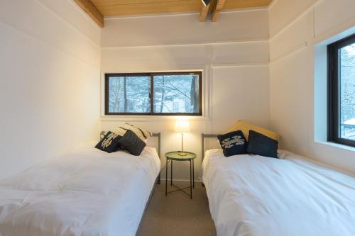 two beds in a small room with a window at Konayuki Cabin Hakuba - Vacation STAY 22044v in Hakuba