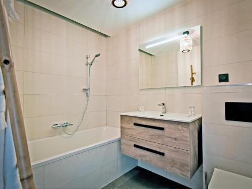 une salle de bain avec un lavabo, une baignoire et un miroir dans l'établissement Spacieux appartement avec terrasse à 2 min des pistes, parking couvert et conciergerie - FR-1-613-98, à Les Allues